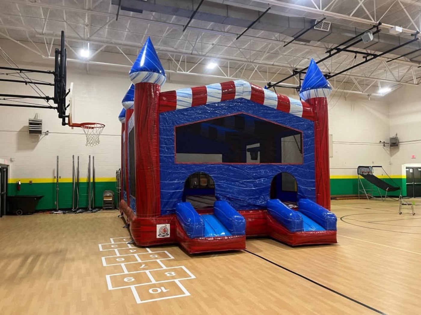Red white and blue candy-striped bounce house with dual entry ramps