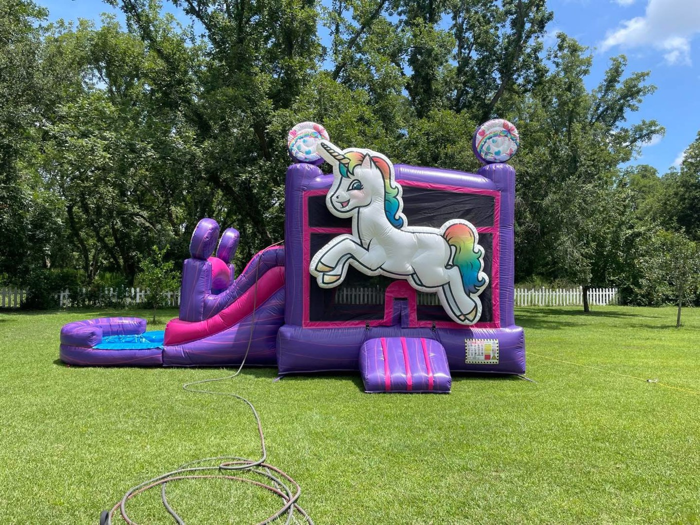 Purple and pink unicorn themed bounce house with slide and splash pool
