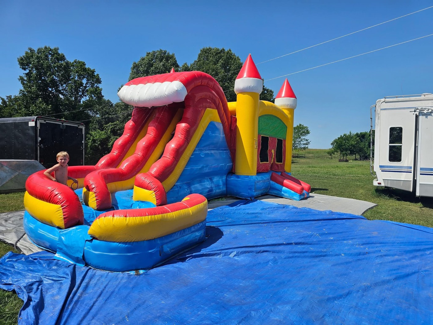 Yellow red and blue castle bounce house with tall red slide and splash pool