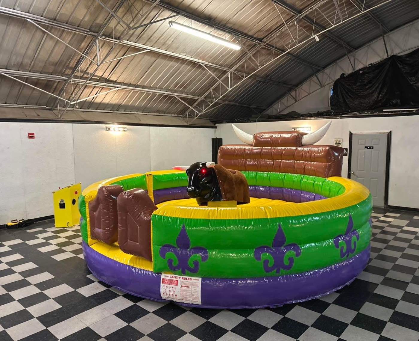 Purple green and gold Mardi Gras themed mechanical bull arena with fleur-de-lis pattern